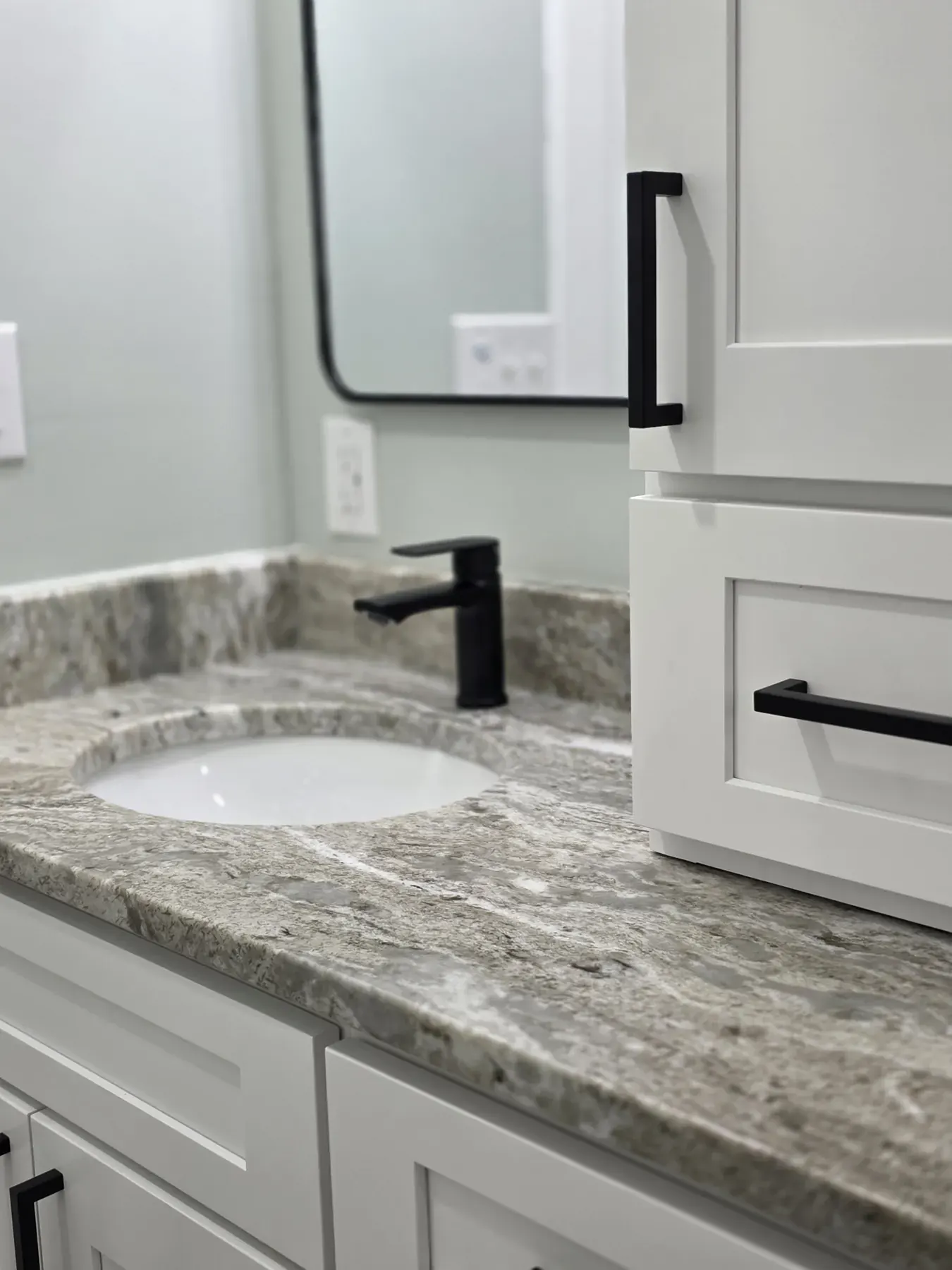 Close-up of a granite vanity top with an undermount sink and black faucet