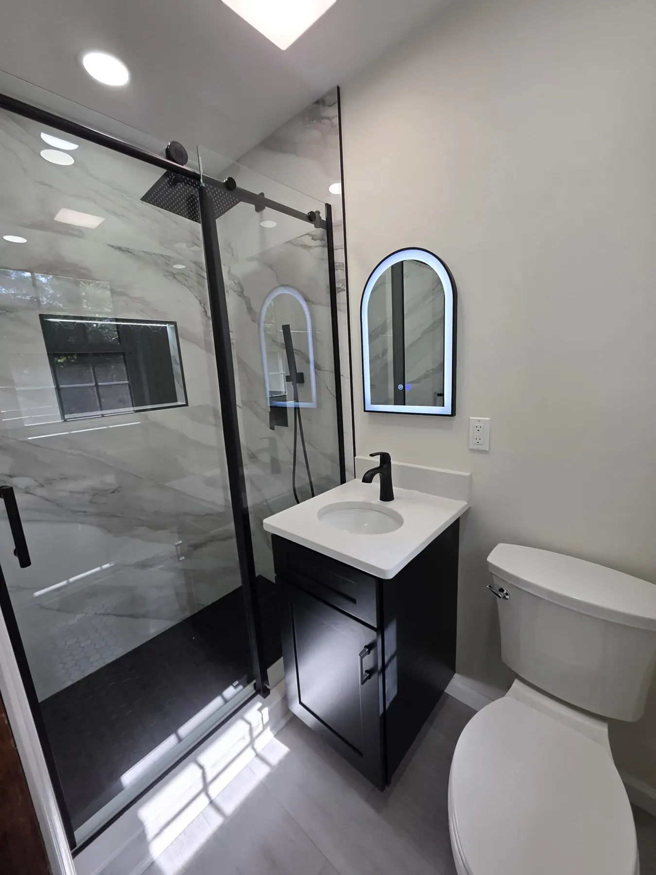 Compact black vanity with a white stone top in a small bathroom