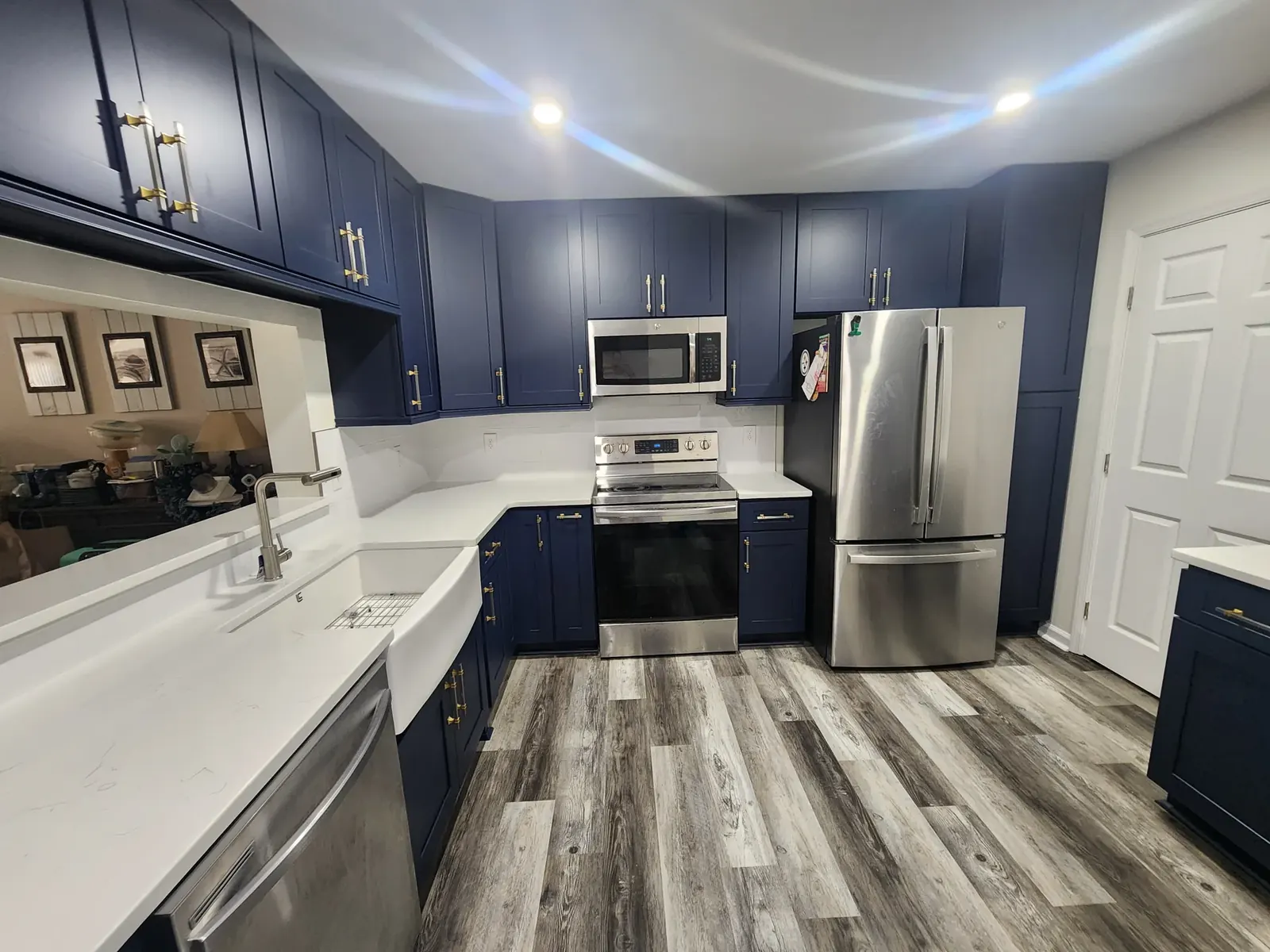 Kitchen with navy shaker cabinets, brass pulls, white stone countertops and a farmhouse sink