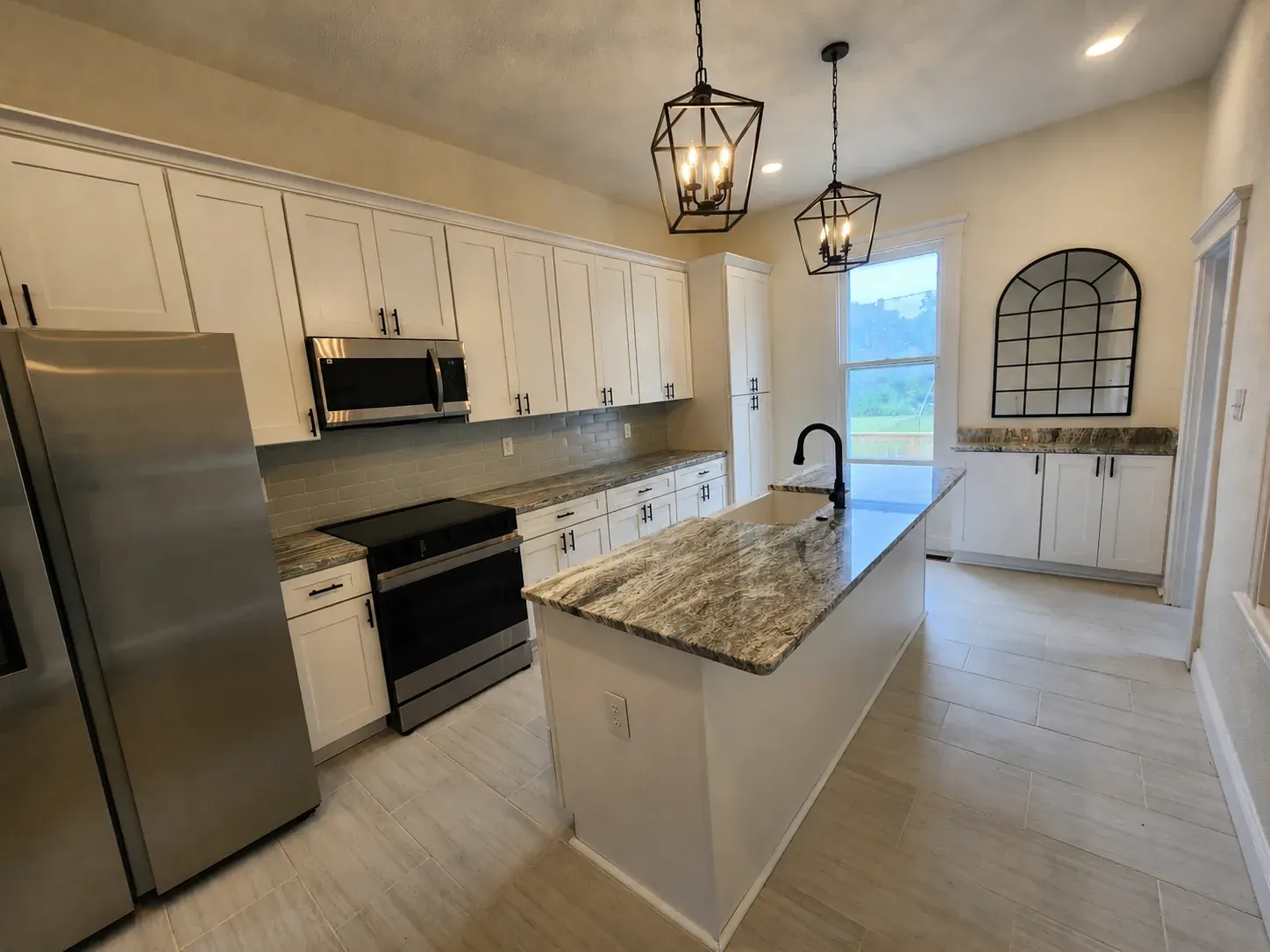 White shaker kitchen with a granite island and black lantern pendants